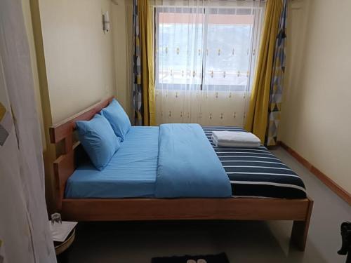 a bedroom with a bed with blue sheets and a window at Bunyonyi Lakefront Leisure Lodge in Kabale