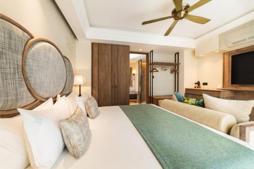 een slaapkamer met een groot bed en een bank bij Maradiva Villas Resort and Spa in Flic-en-Flac