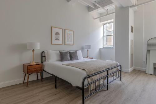 a white bedroom with a bed and a night stand at Central Square 2br w fitness close to dining BOS-993 in Cambridge