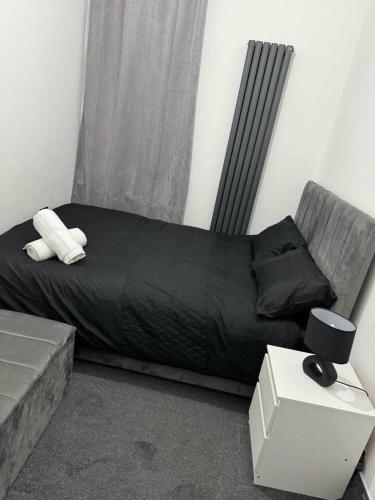 a bed with a black comforter and a couch at Elegant 2-Bedroom Apartment near city centre in Birmingham