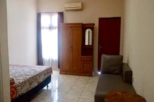 a bedroom with a bed and a chair and a mirror at Aryani Suites Syariah in Jakarta