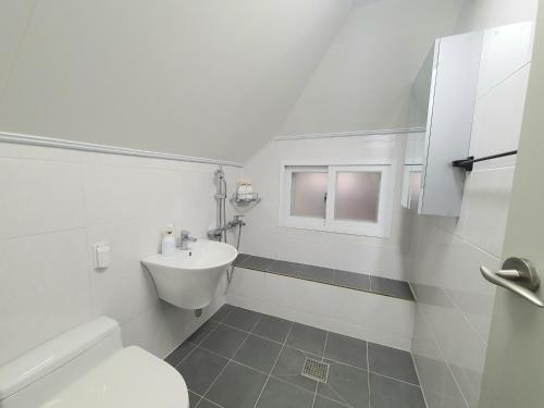 a white bathroom with a toilet and a sink at P house in Seoul