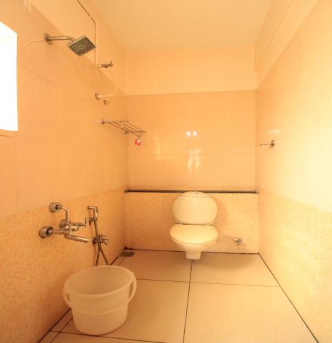 a bathroom with a toilet and a bucket in it at Hotel Rathnavel Towers in Chennai