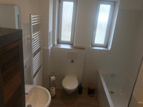 ein weißes Bad mit einem WC und 2 Fenstern in der Unterkunft Mimalou Apartment in Zwickau in Zwickau