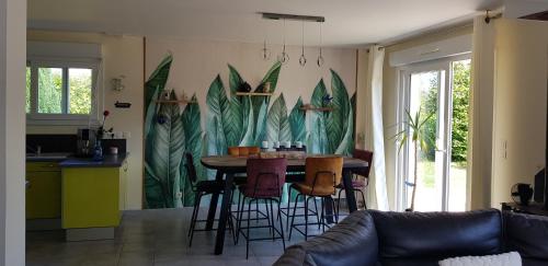 un salon avec une table et une cuisine avec des plantes sur le mur dans l'établissement maison privative la fougere, à La Haye-dʼEctot