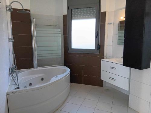 een badkamer met een bad, een wastafel en een raam bij Olga Luxury Beach Front Villas in Lachaniá