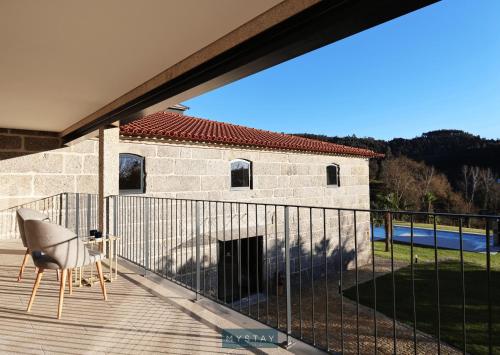 a balcony with a chair and a building at MyStay - Casa d'Henrique in Vieira do Minho