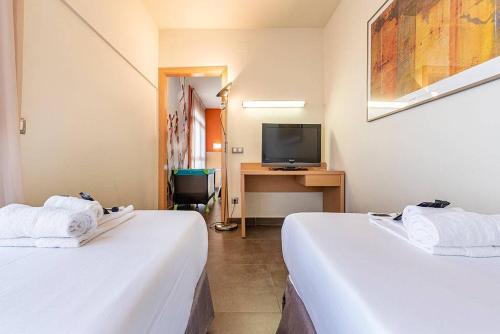 a hotel room with two beds and a television at Hotel Pere III El Gran in Vilafranca del Penedès