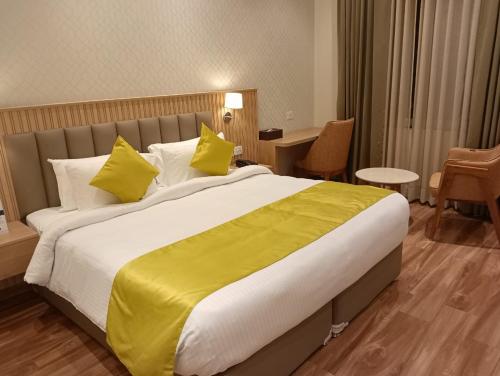 a hotel room with a large bed with yellow pillows at ANTILIA BY ZION in Sonīpat