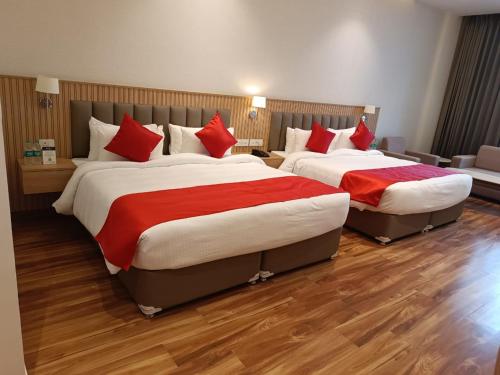 two beds in a hotel room with red pillows at ANTILIA BY ZION in Sonīpat