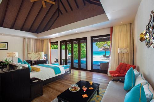 a bedroom with a bed and a living room at Atmosphere Kanifushi - Premium All Inclusive with Free Transfers in Lhaviyani Atoll