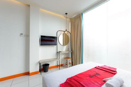 een slaapkamer met een wit bed en een spiegel bij RedDoorz near Mangga Dua Mall in Jakarta