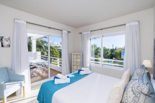 a white bedroom with a large bed and a balcony at Al-411 Estepona - Apartment - Alcazaba Lagoon in Estepona