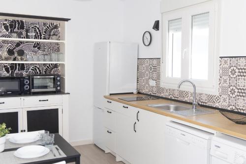 een witte keuken met een wastafel en een magnetron bij Villa ANDROMEDA in Chiclana de la Frontera