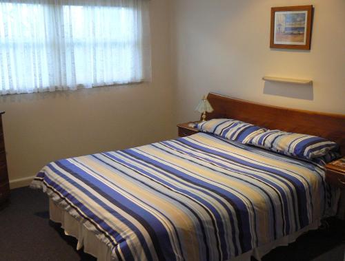 a bedroom with a bed with a striped blanket at Rosebud Beach Unit 200 mt to Beach Late checkout in Rosebud