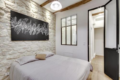 une chambre avec un lit blanc et un mur en pierre dans l'établissement Bastille - Gare de Lyon - Appartement familial, à Paris