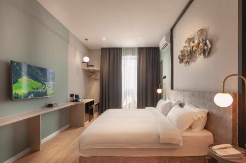 ein Schlafzimmer mit einem großen weißen Bett in einem Zimmer in der Unterkunft FUHOTEL in Bukit Mertajam