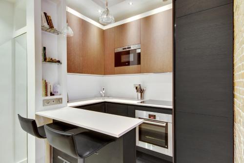 une cuisine avec un comptoir blanc et un évier dans l'établissement Bastille - Gare de Lyon - Appartement familial, à Paris