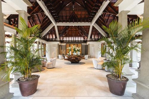 an indoor lobby with palm trees in pots at Maradiva Villas Resort and Spa in Flic-en-Flac