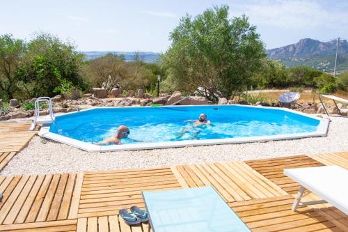 two people swimming in a swimming pool in a backyard at Pasare Glamping_AnglonaRuralExperience in Perfugas