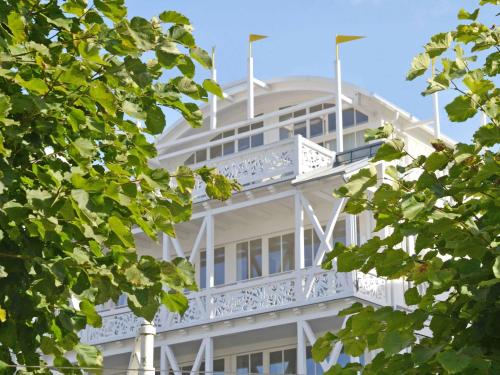a white building with a balcony and trees at Villa "Johanna" Sellin - WG11 mit Kamin und großer Terrasse in Ostseebad Sellin