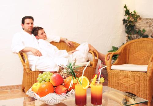 two men sitting in wicker chairs with a table of fruit at Landhotel Haagerhof in Aigen im Mühlkreis