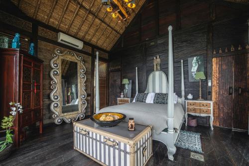 a bedroom with a bed and a mirror and a table at Beachfront Villa Laut Tabanan in Tabanan