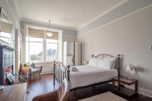 een slaapkamer met een bed, een stoel en een raam bij Pass the Keys Beautiful, traditional 2 bed flat w free parking in Glasgow
