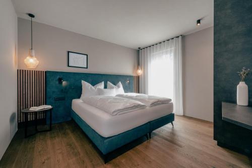 - une chambre avec un grand lit et un mur bleu dans l'établissement LA LIBELLA - slow living Suites, à Merano
