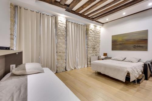 une chambre avec deux lits et un tableau au mur dans l'établissement Marais - Appartement Parisien pour 5 personnes, à Paris