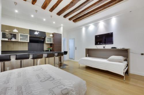 Cet appartement comprend une chambre avec un lit blanc et une cuisine. dans l'établissement Marais - Appartement Parisien pour 5 personnes, à Paris