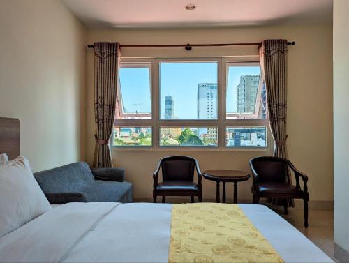 a bedroom with a bed and chairs and a window at 中青秋果酒店 True Go Hotel in Phnom Penh