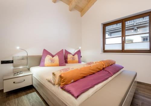 1 dormitorio con 1 cama con almohadas de color rosa y naranja en Am Dorfbrunnen, en Oetz
