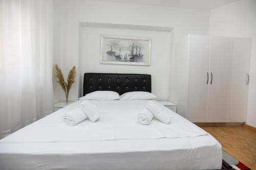 a white bedroom with a large white bed with two pillows at Noa Apartments in Vlorë