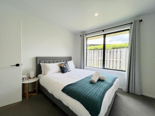 een slaapkamer met een bed en een groot raam bij Leisure Holiday Home Lake Hayes Easte Queenstown in Arrowtown