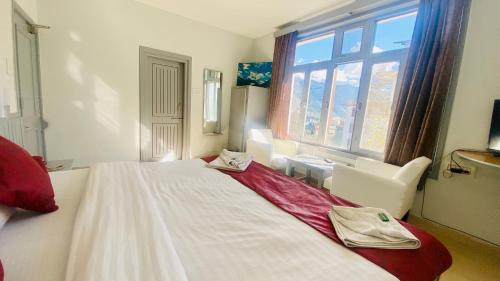 una camera da letto con un grande letto bianco e una finestra di Hotel Himalayan Meadows a Manāli