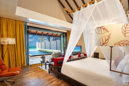 a bedroom with a canopy bed with a view of the ocean at Atmosphere Kanifushi - Premium All Inclusive with Free Transfers in Lhaviyani Atoll