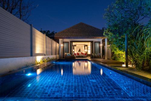 a swimming pool in front of a house at night at Atmosphere Kanifushi - Premium All Inclusive with Free Transfers in Lhaviyani Atoll
