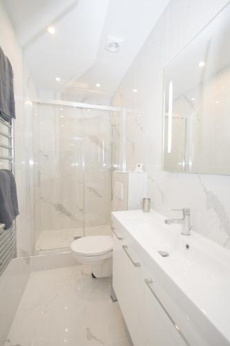 une salle de bain blanche avec toilettes et douche dans l'établissement Marais - Appartement Parisien pour 5 personnes, à Paris