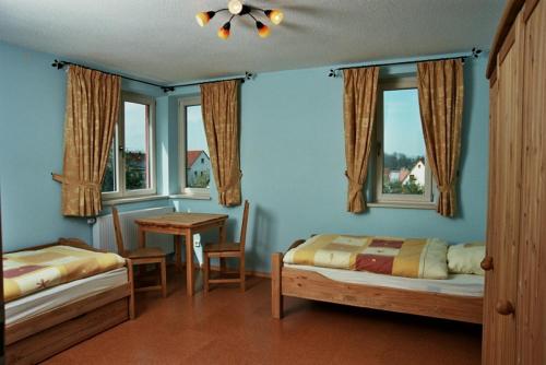 Un dormitorio con dos camas y una mesa y ventanas. en Ferienwohnung „Rosarium“, en Gunzenhausen