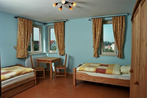 a bedroom with two beds and a table and windows at Ferienwohnung „Rosarium“ in Gunzenhausen