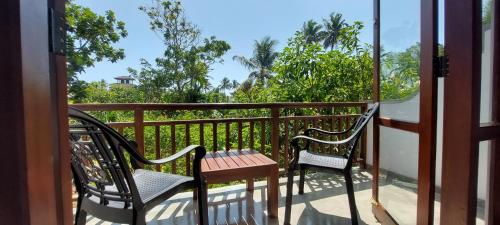 a balcony with two chairs and a wooden table at Green Grove in Matara