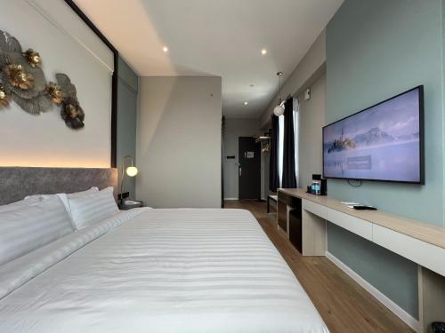 a bedroom with a large bed and a flat screen tv at FUHOTEL in Bukit Mertajam