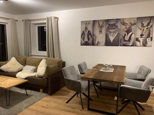 a living room with a couch and a table and chairs at Almlodge Flachau in Flachau