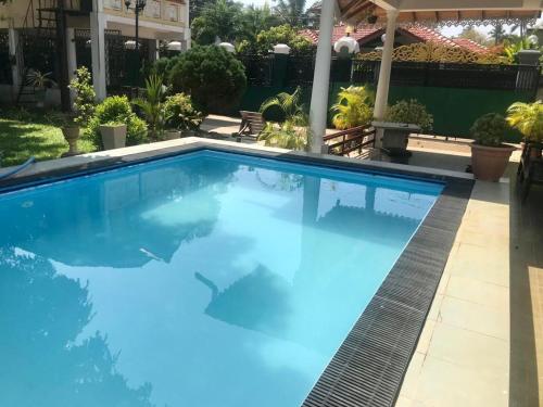 a large swimming pool with blue water in a yard at Kingz and Queenz - Negombo in Negombo