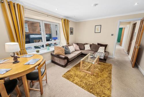 a living room with a couch and a table at Central Stay on Main st- Harbour Views in Oban