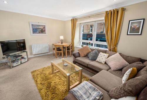 a living room with a couch and a table at Central Stay on Main st- Harbour Views in Oban