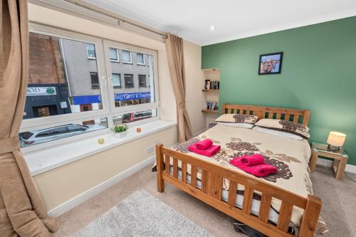 een slaapkamer met een bed met roze slippers erop bij Argyll Apartments - George Street, Oban in Oban