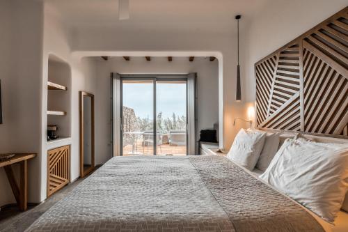 a bedroom with a large bed with a large wooden headboard at Alissachni Mykonos in Psarou