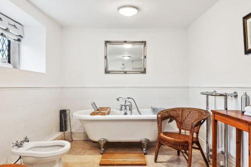 a bathroom with a tub and a toilet and a chair at Old Hall Middle - Mayfield in Ashbourne